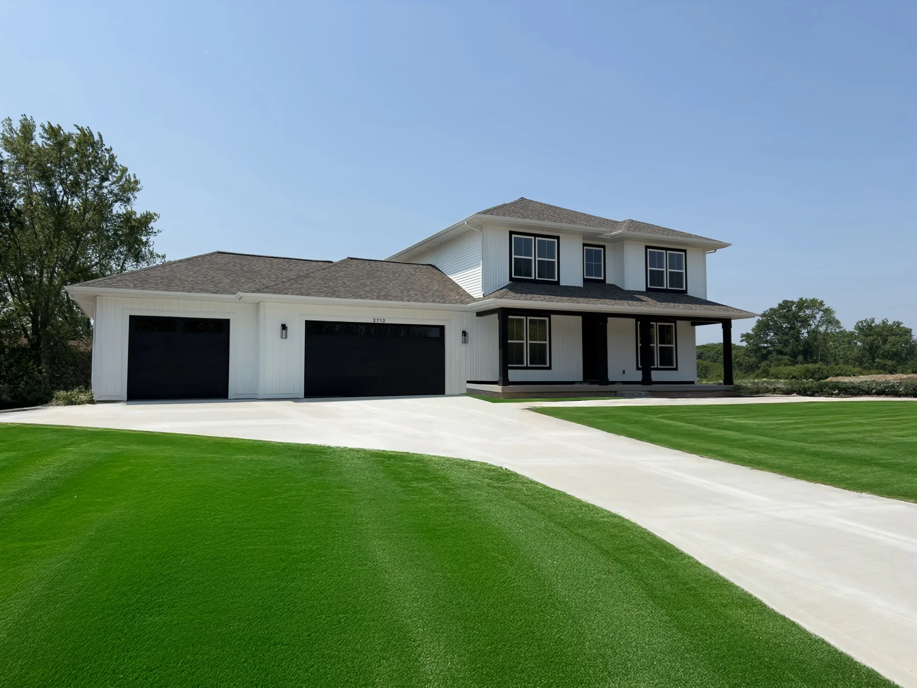 A finished custom home built by LOYL Construction, white siding with black garage doors