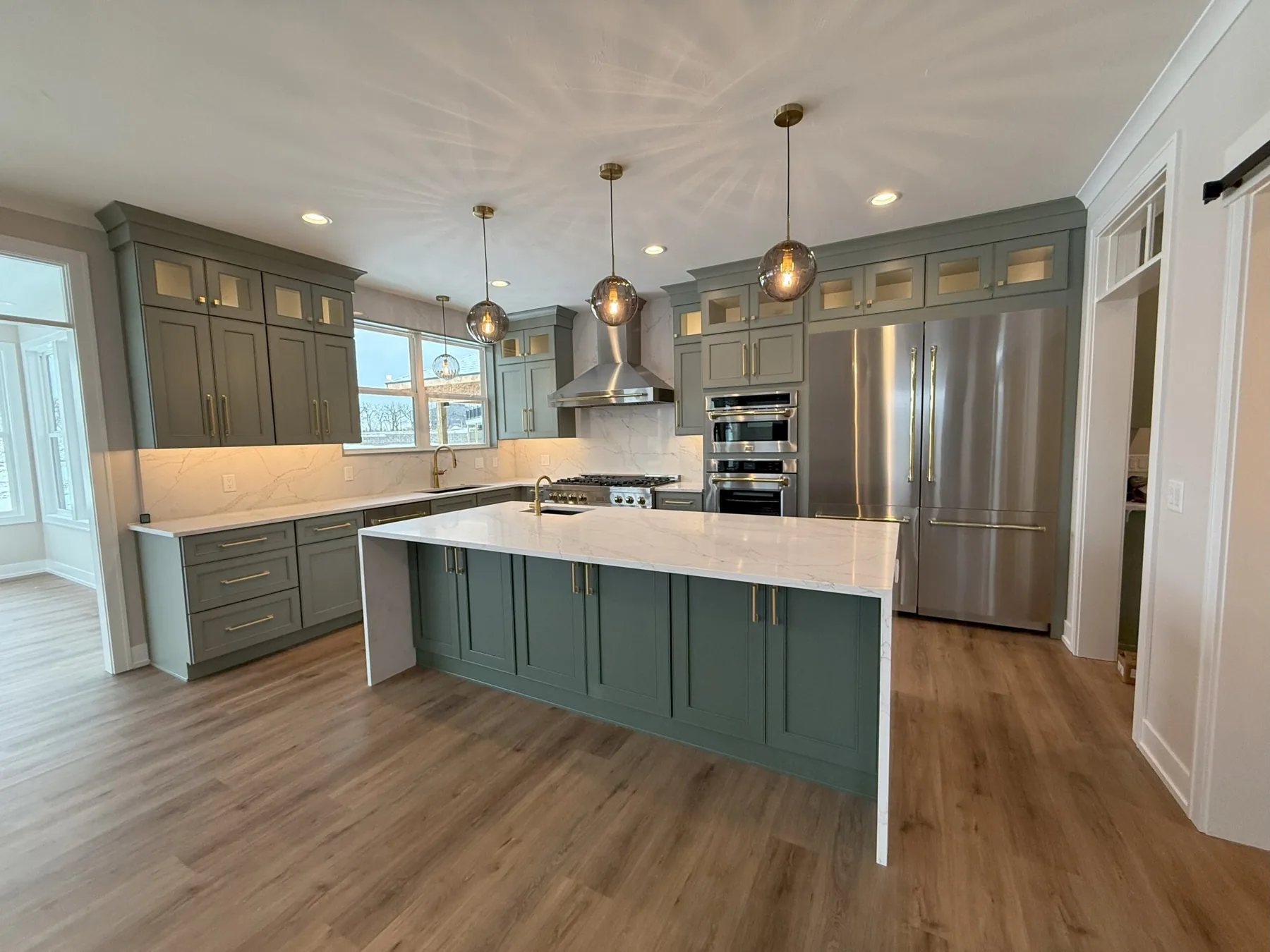 Remodeled kitchen with green cabinetry and a large island